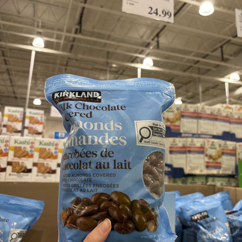 person holding bag of Kirkland Signature chocolate-covered almonds at costco