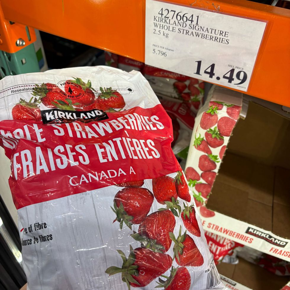 person holding bag of Kirkland Signature frozen whole strawberries