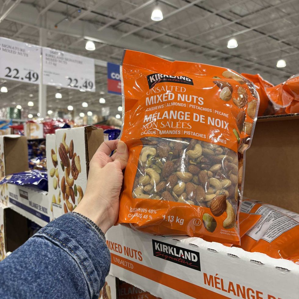 person holding bag of Kirkland Signature mixed nuts at costco