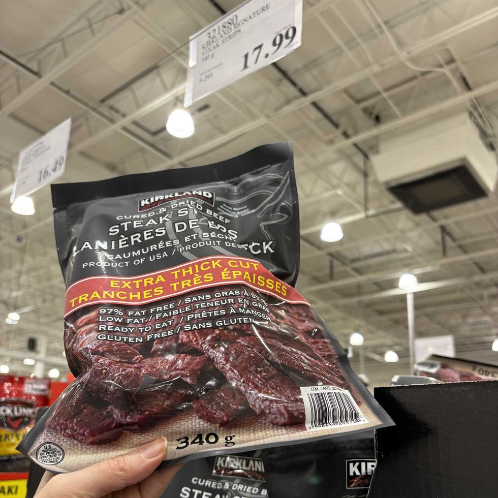 person holding bag of Kirkland Signature steak strips at costco