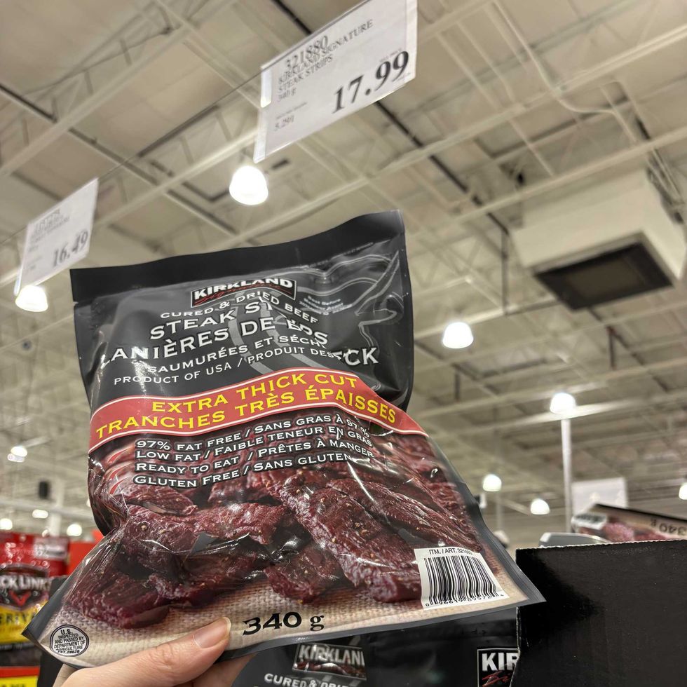 person holding bag of Kirkland Signature steak strips at costco