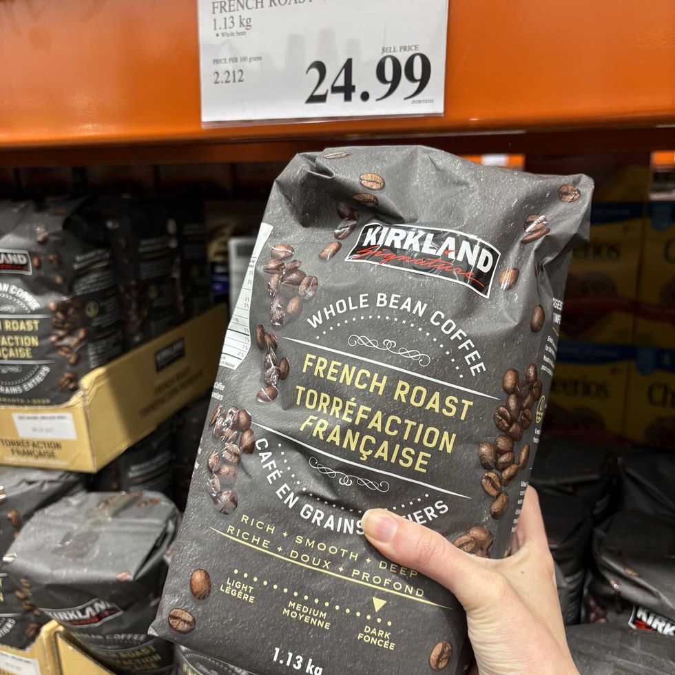 person holding bag of \u200bKirkland Signature French roast coffee at costco