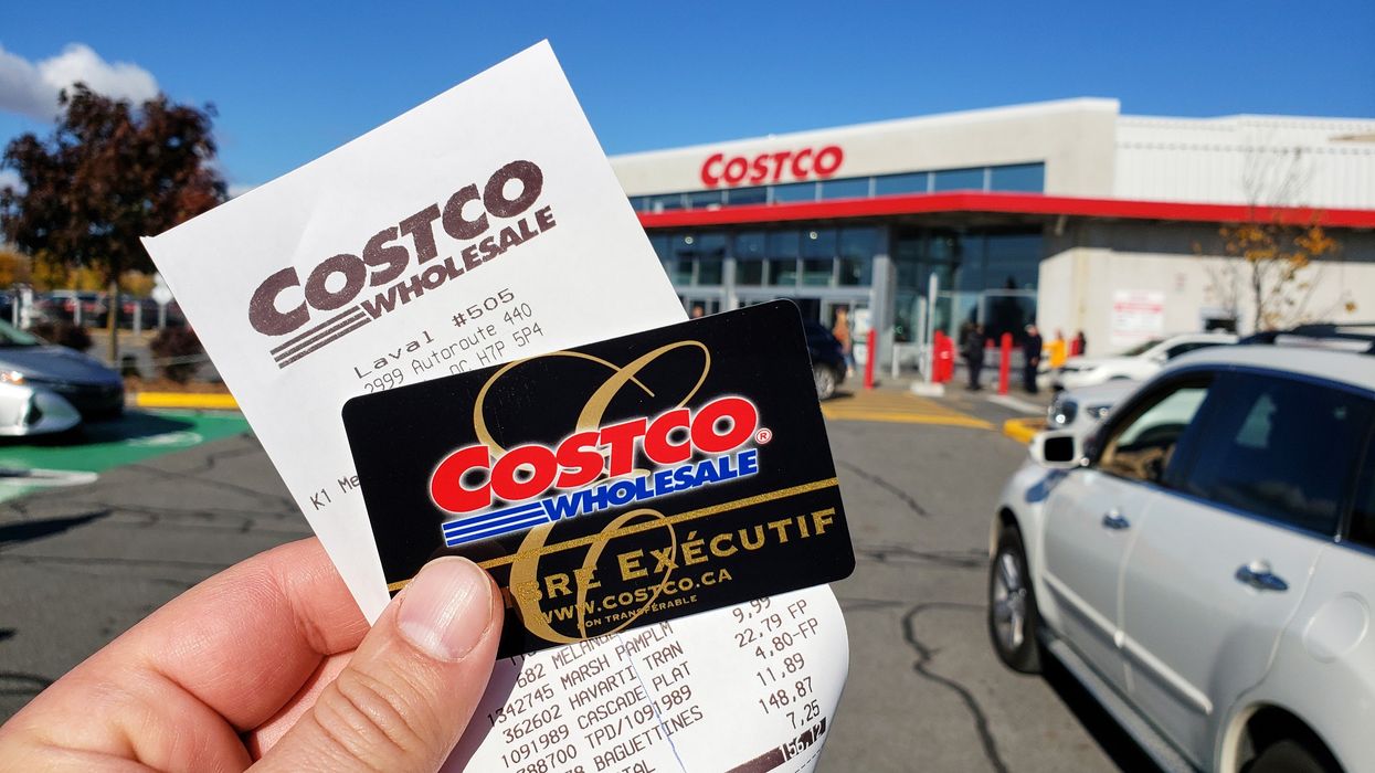 person holding black costco membership card and costco receipt outside a costco location