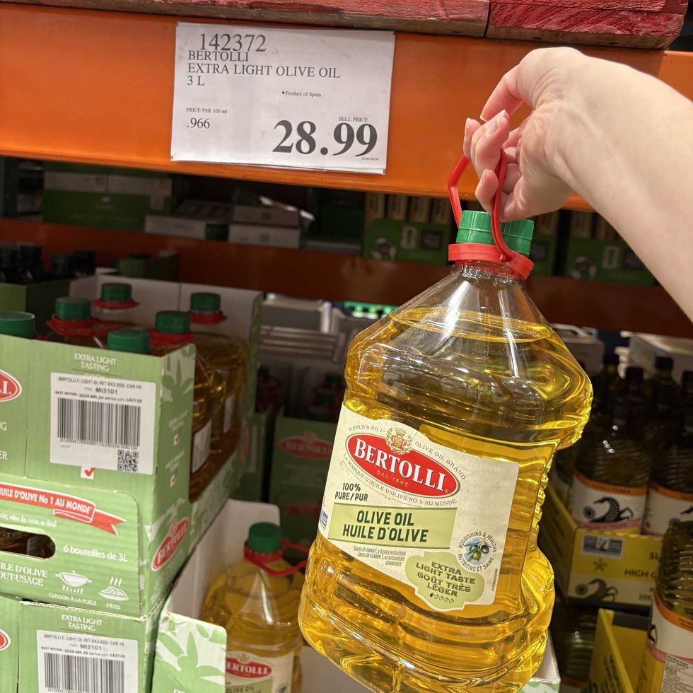 person holding bottle of Bertolli olive oil at Costco