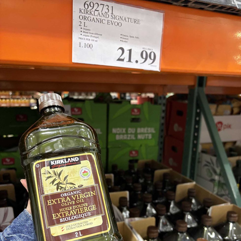 person holding bottle of Kirkland Signature extra virgin olive oil at costco