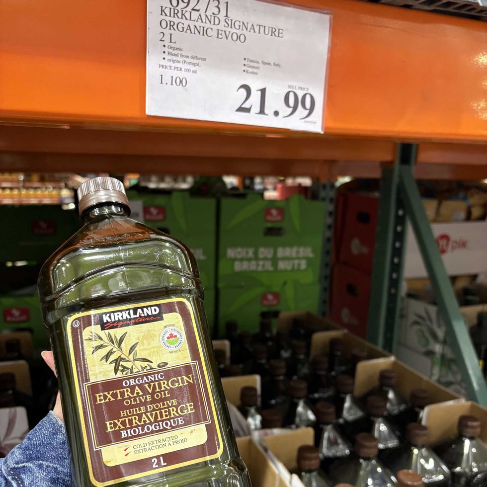 person holding bottle of Kirkland Signature extra virgin olive oil at costco