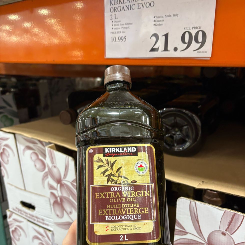 person holding bottle of Kirkland Signature extra virgin olive oil