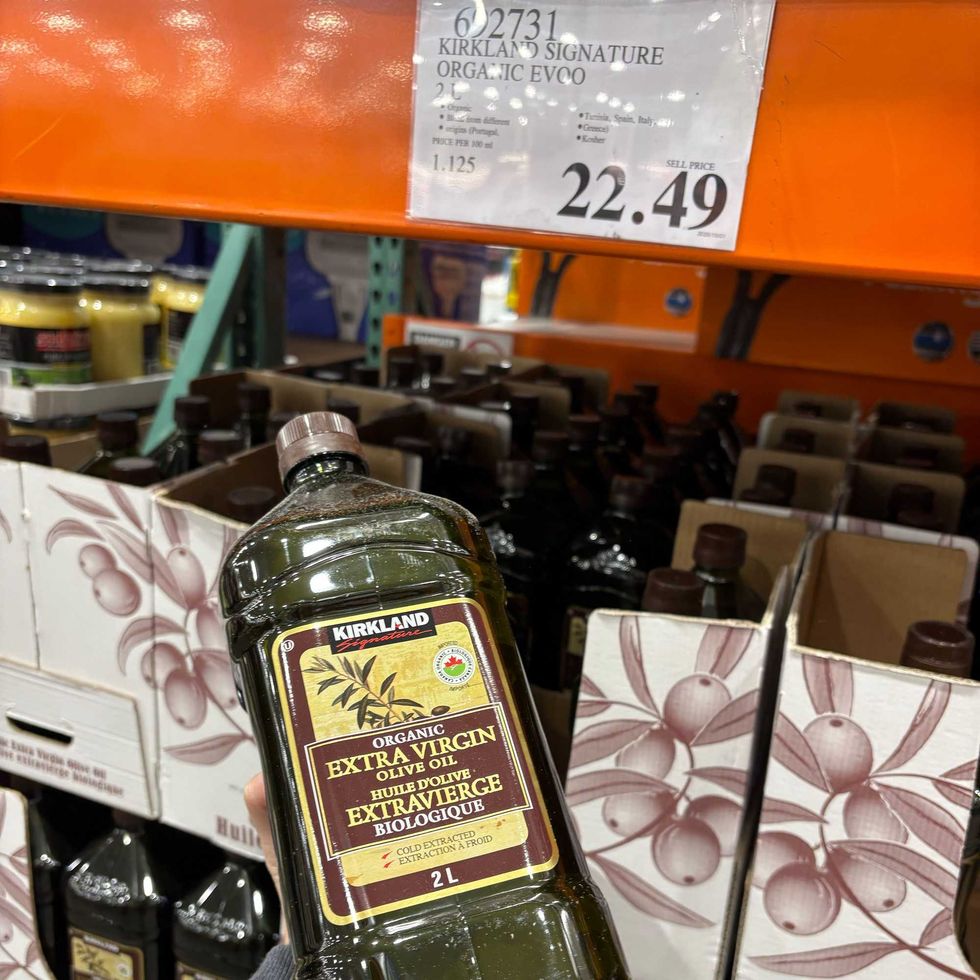 person holding bottle of Kirkland Signature extra virgin olive oil