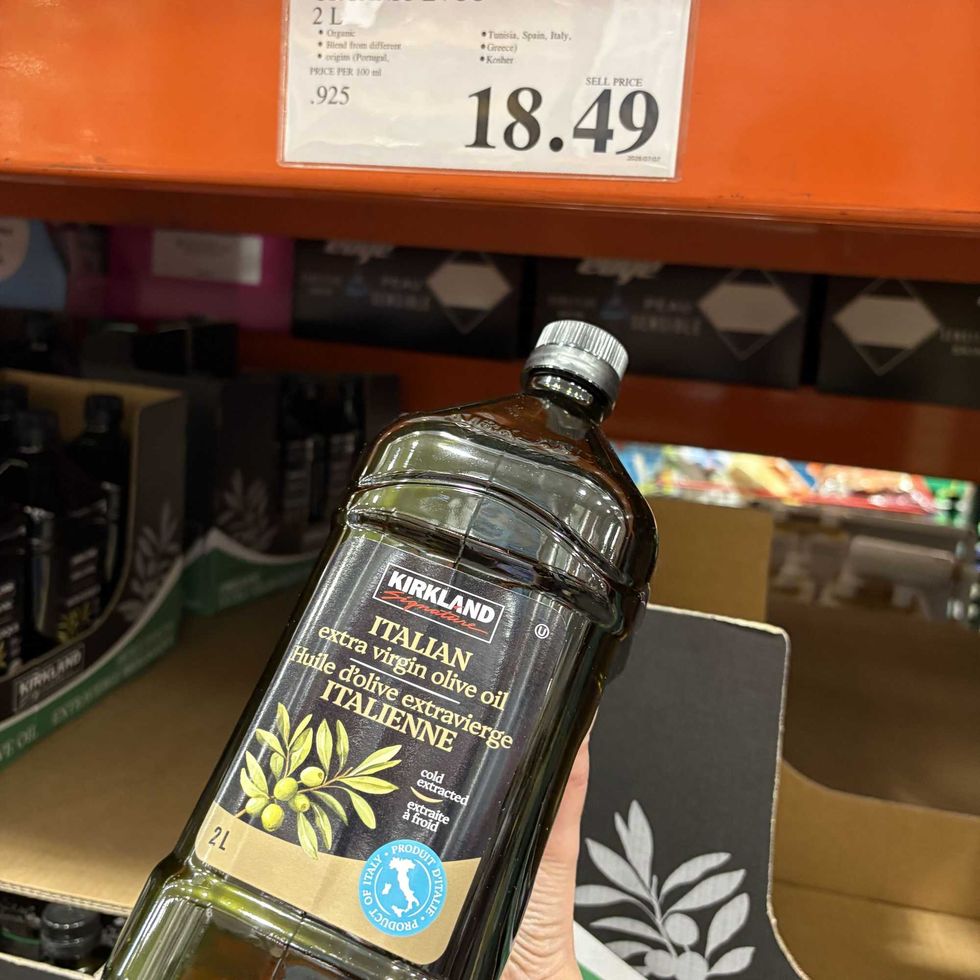 person holding bottle of Kirkland Signature Italian extra virgin olive oil at costco