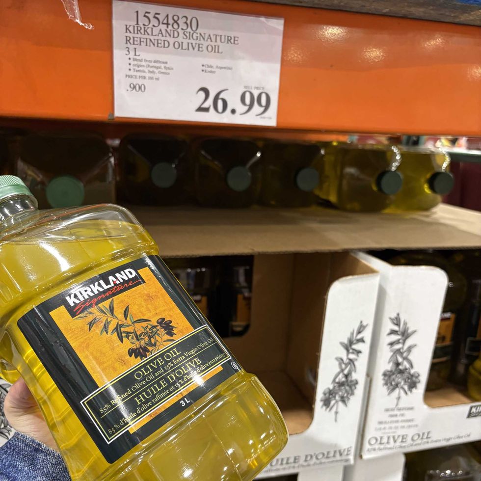 person holding bottle of Kirkland Signature light olive oil at costco
