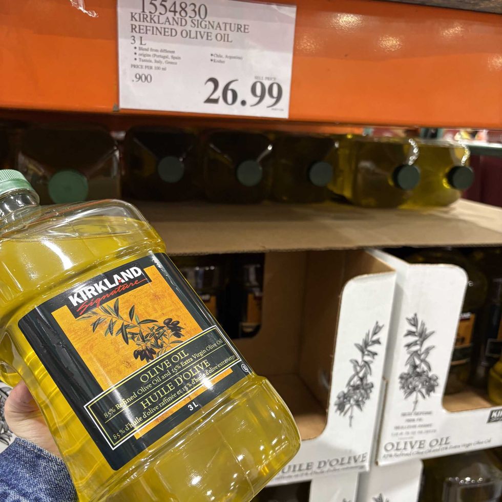 person holding bottle of Kirkland Signature light olive oil at costco