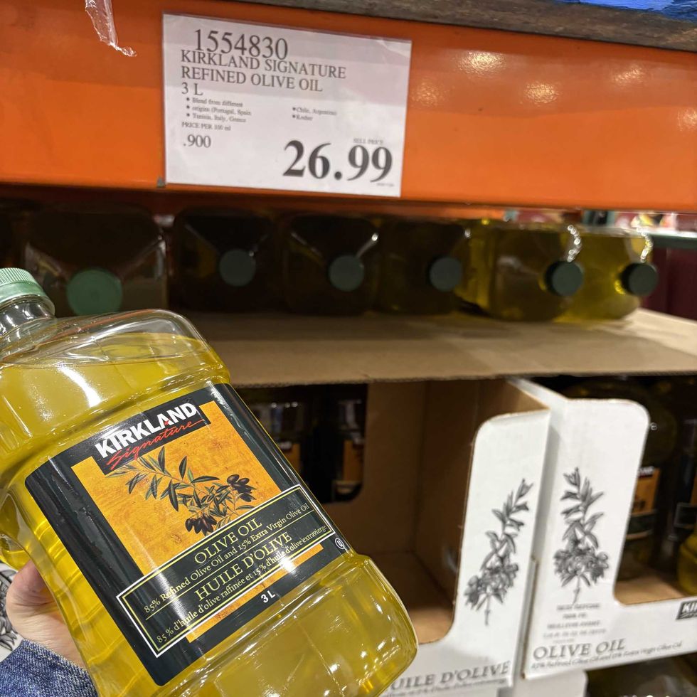 person holding bottle of Kirkland Signature light olive oil at costco