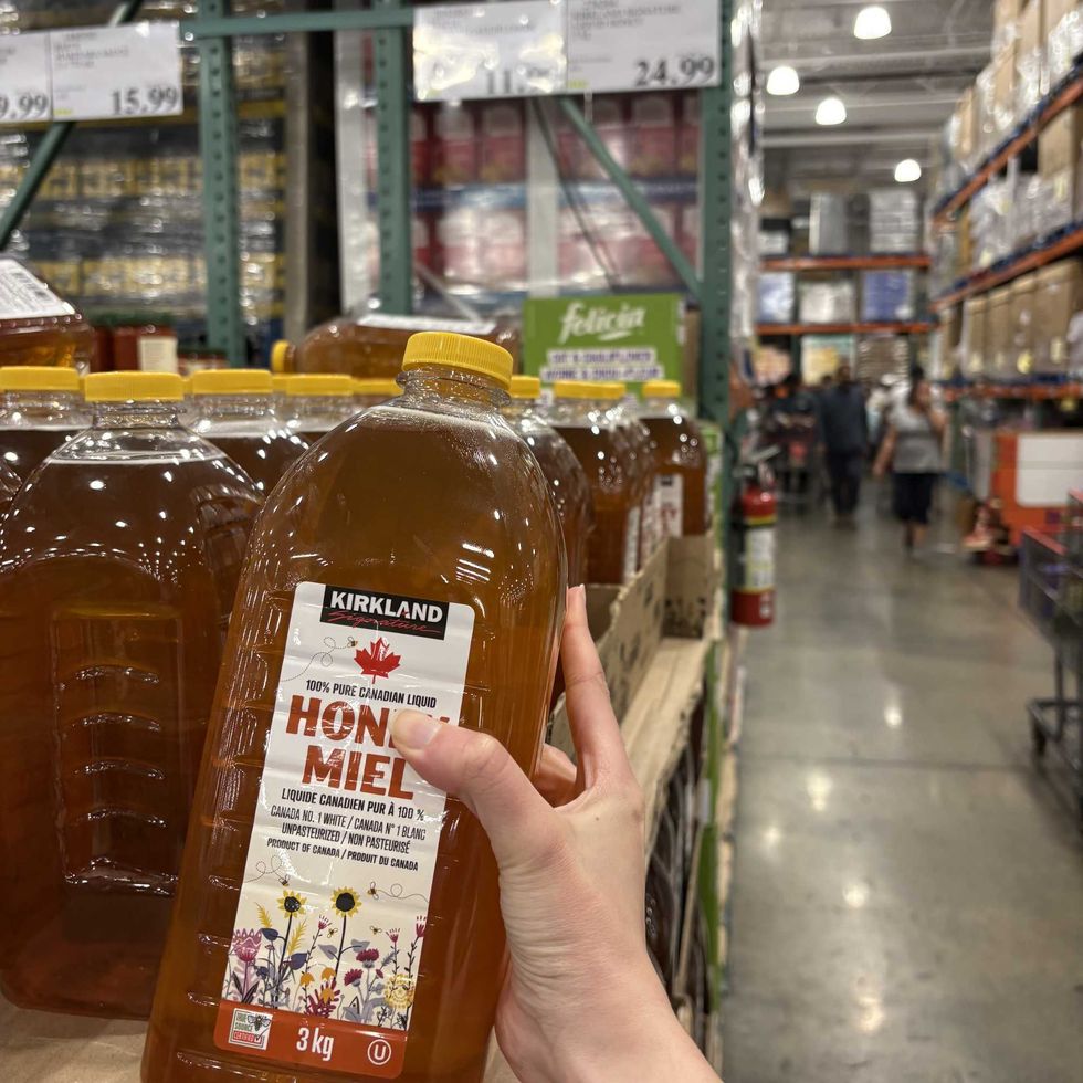 person holding bottle of Kirkland Signature liquid honey at Costco