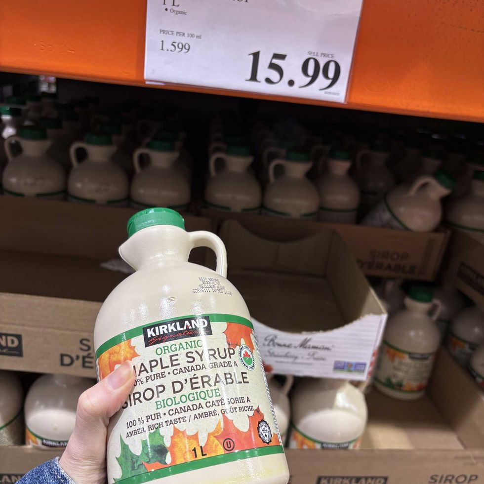 person holding bottle of Kirkland Signature maple syrup at costco