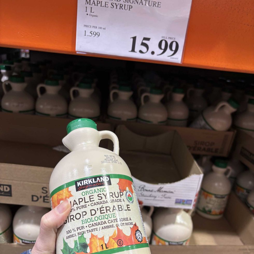 person holding bottle of Kirkland Signature maple syrup at costco