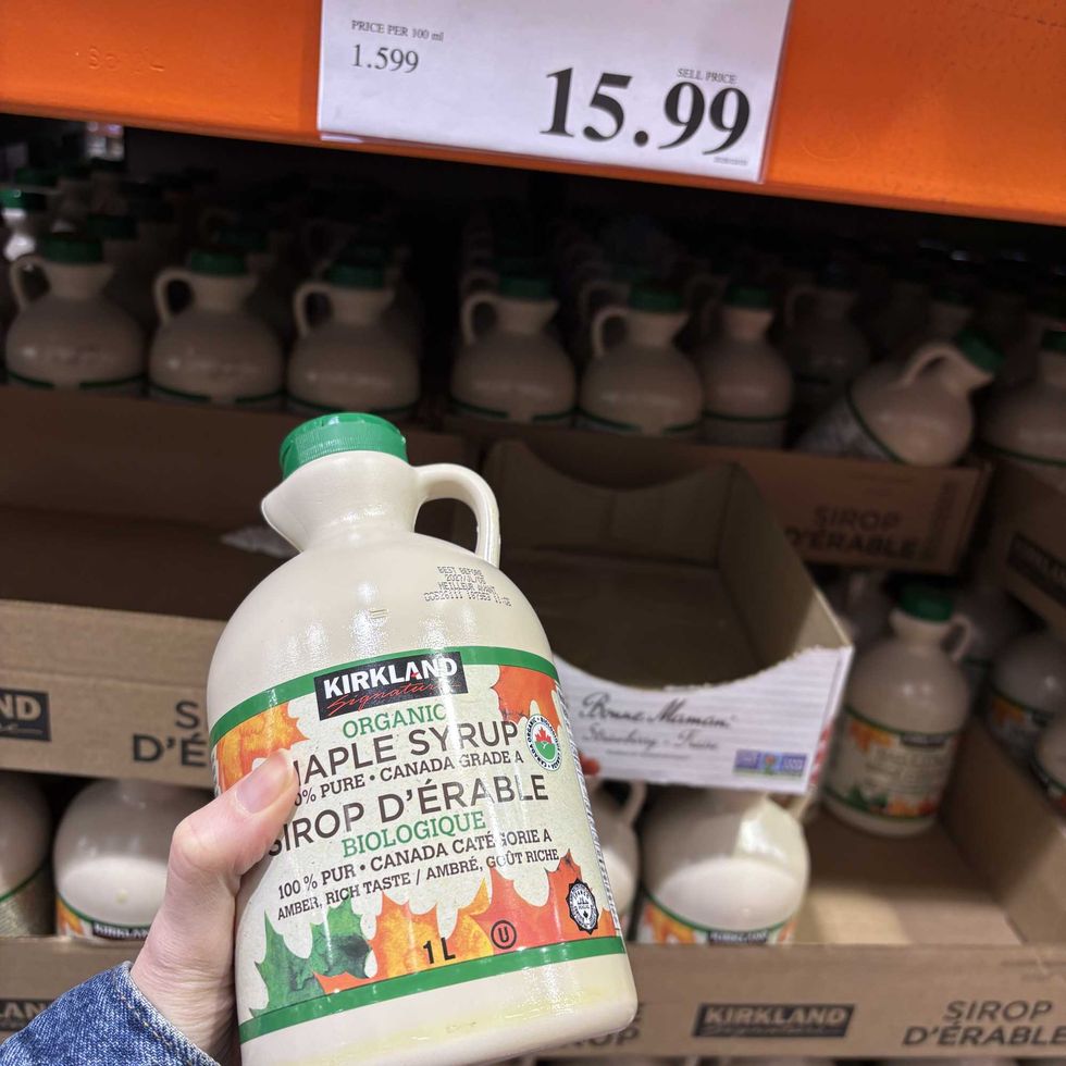 person holding bottle of Kirkland Signature maple syrup at costco