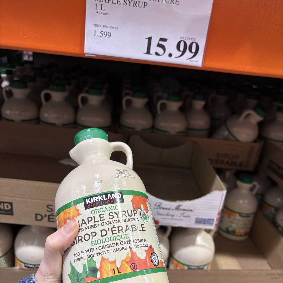 person holding bottle of Kirkland Signature maple syrup at costco