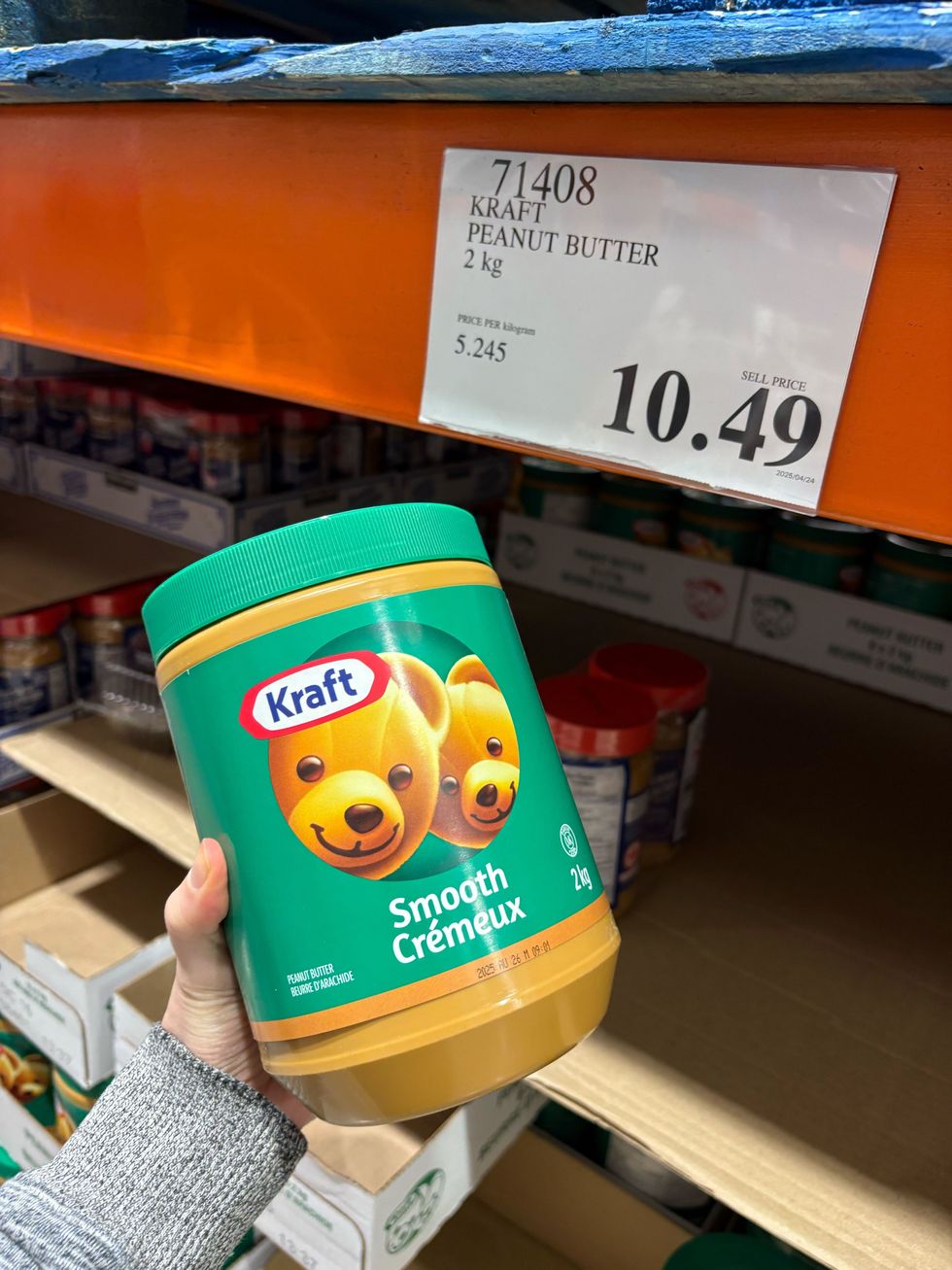 person holding bottle of kraft peanut butter at costco