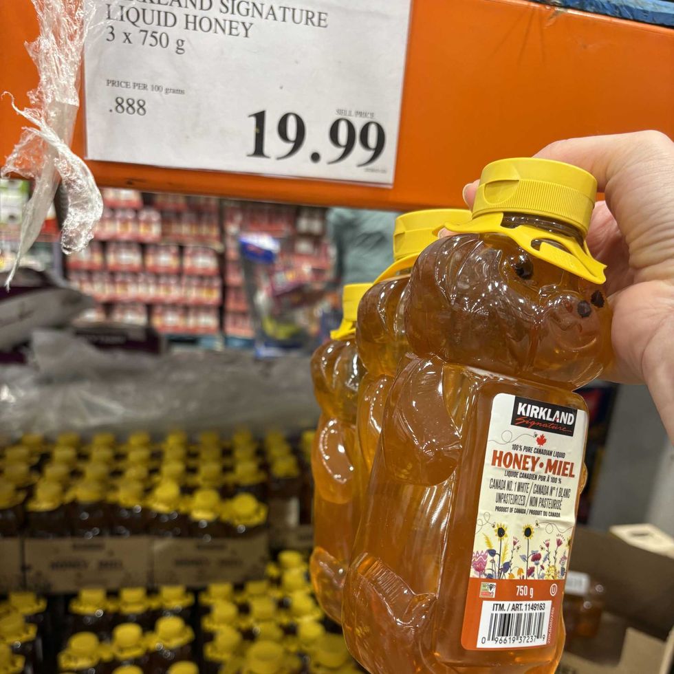 person holding bottles of Kirkland Signature liquid honey at costco