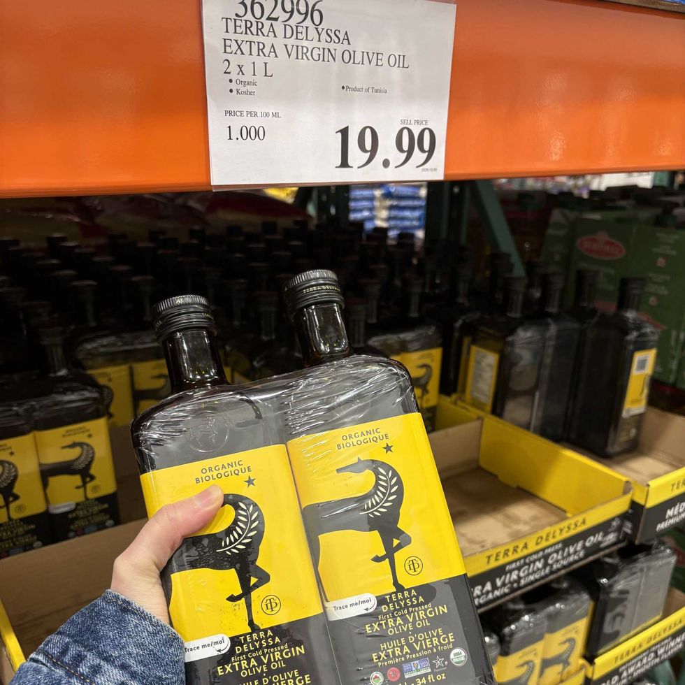 person holding bottles of Terra Delyssa olive oil at costco