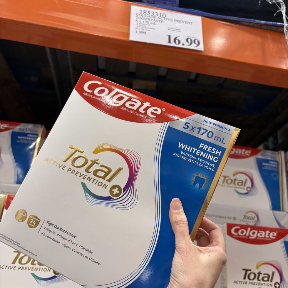 person holding box of Colgate toothpaste tubes at Costco