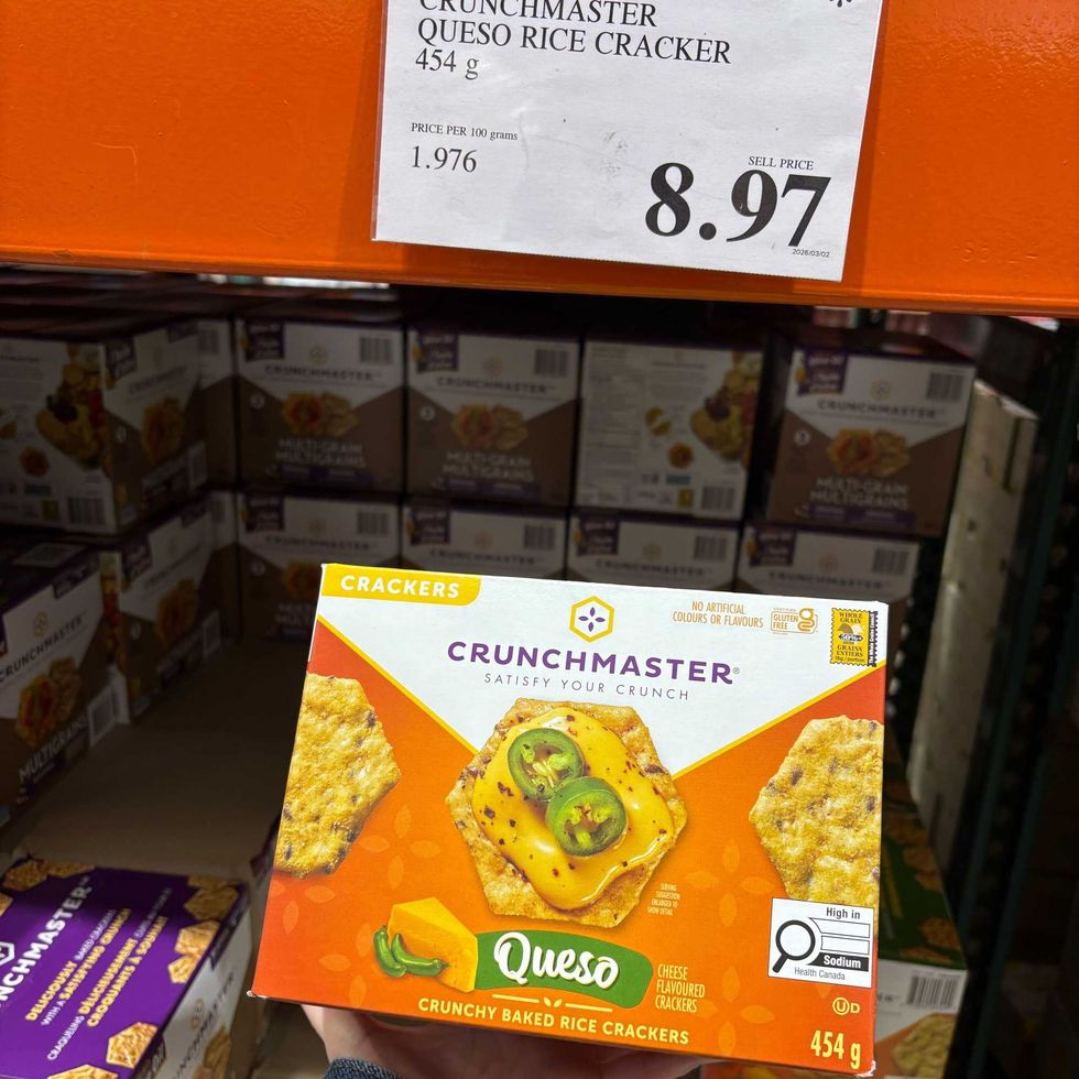 person holding box of Crunchmaster queso-flavoured rice crackers at costco