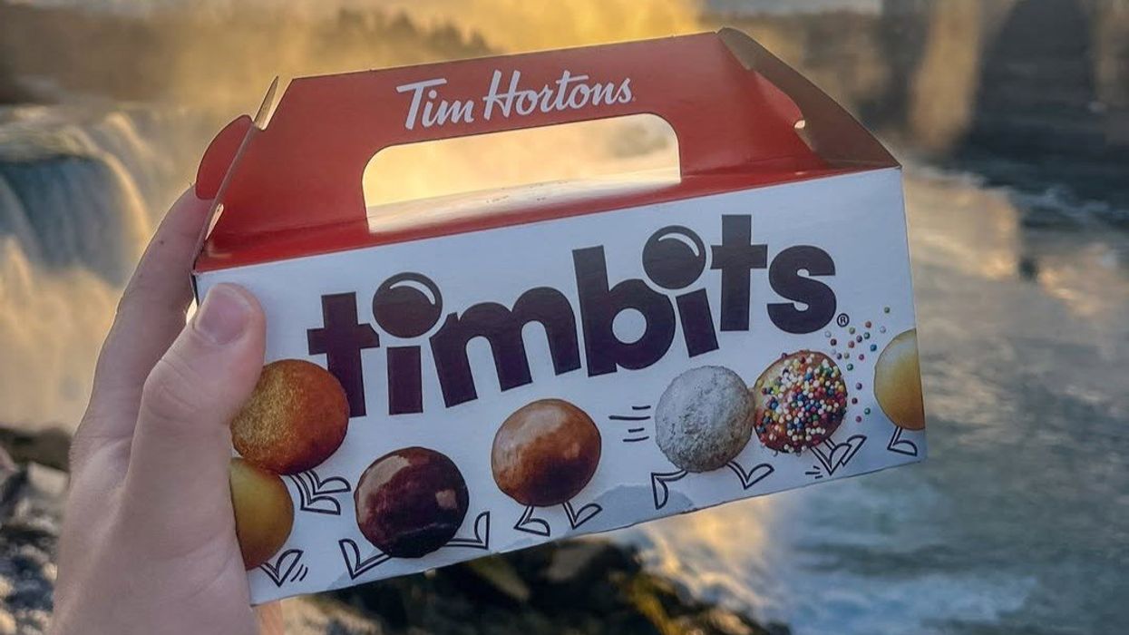 person holding box of tim hortons timbits