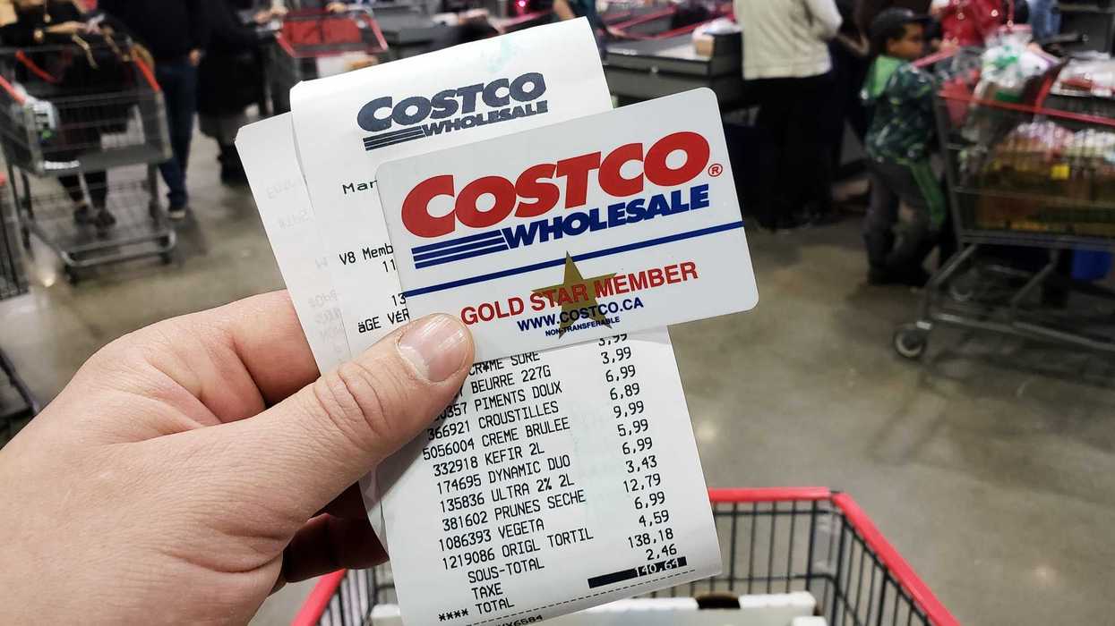 person holding costco membership card and receipt at checkout in store
