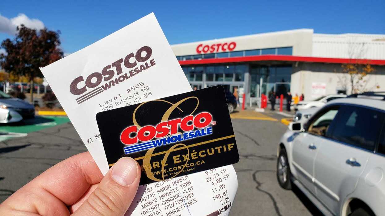 person holding costco membership card and receipt in front of costco store in canada