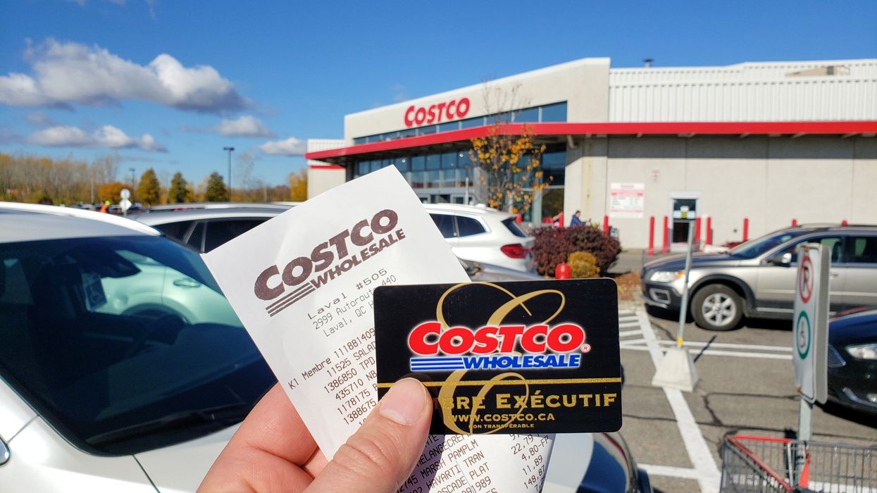 person holding costco membership card and receipt outside a costco store in canada