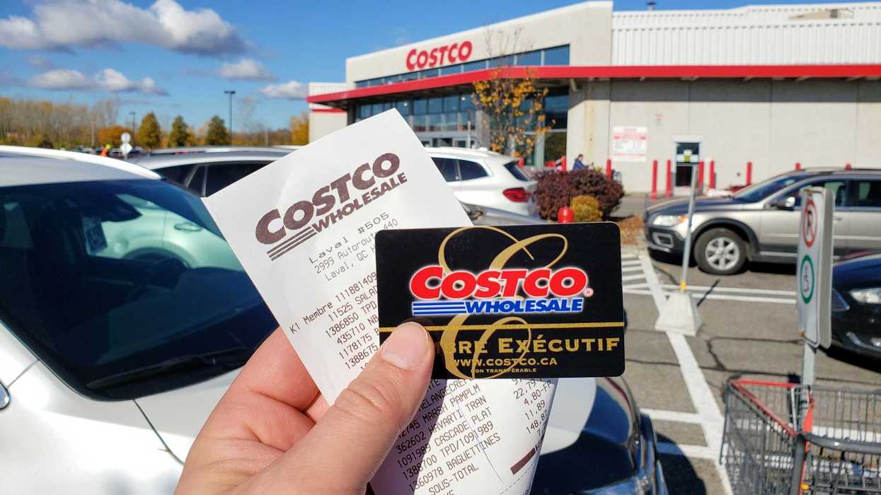 person holding costco membership card and receipt with store in the background