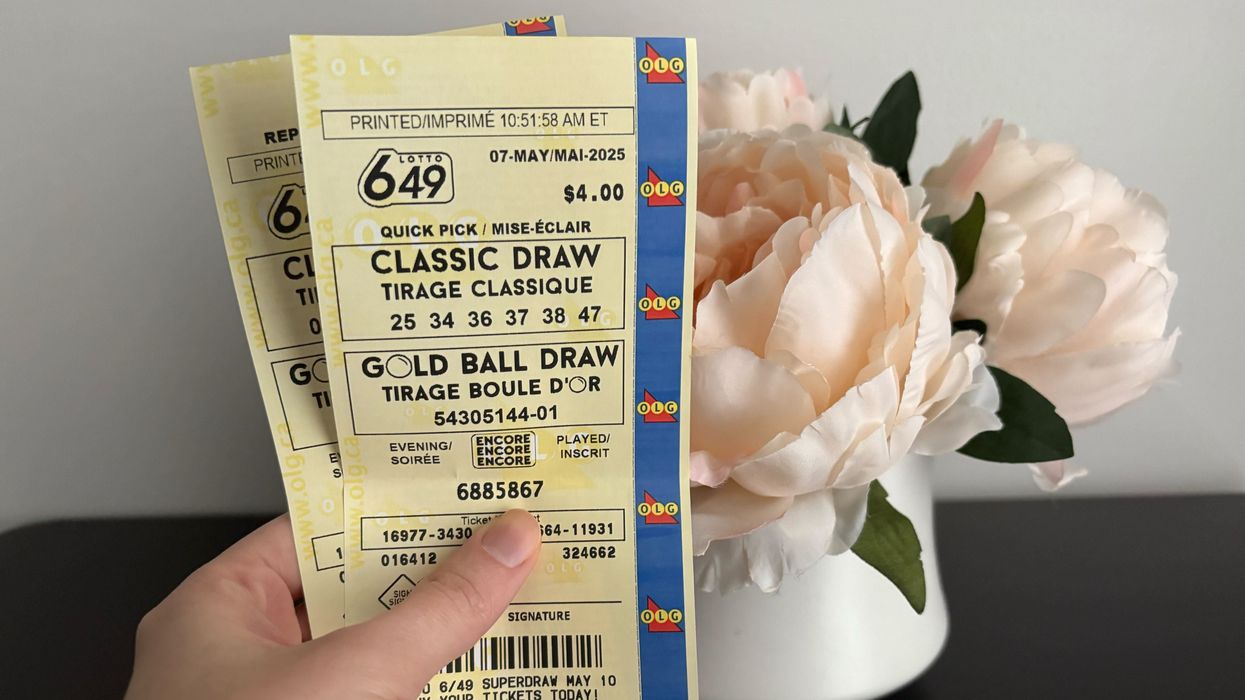 person holding lotto 6/49 tickets in front of flowers