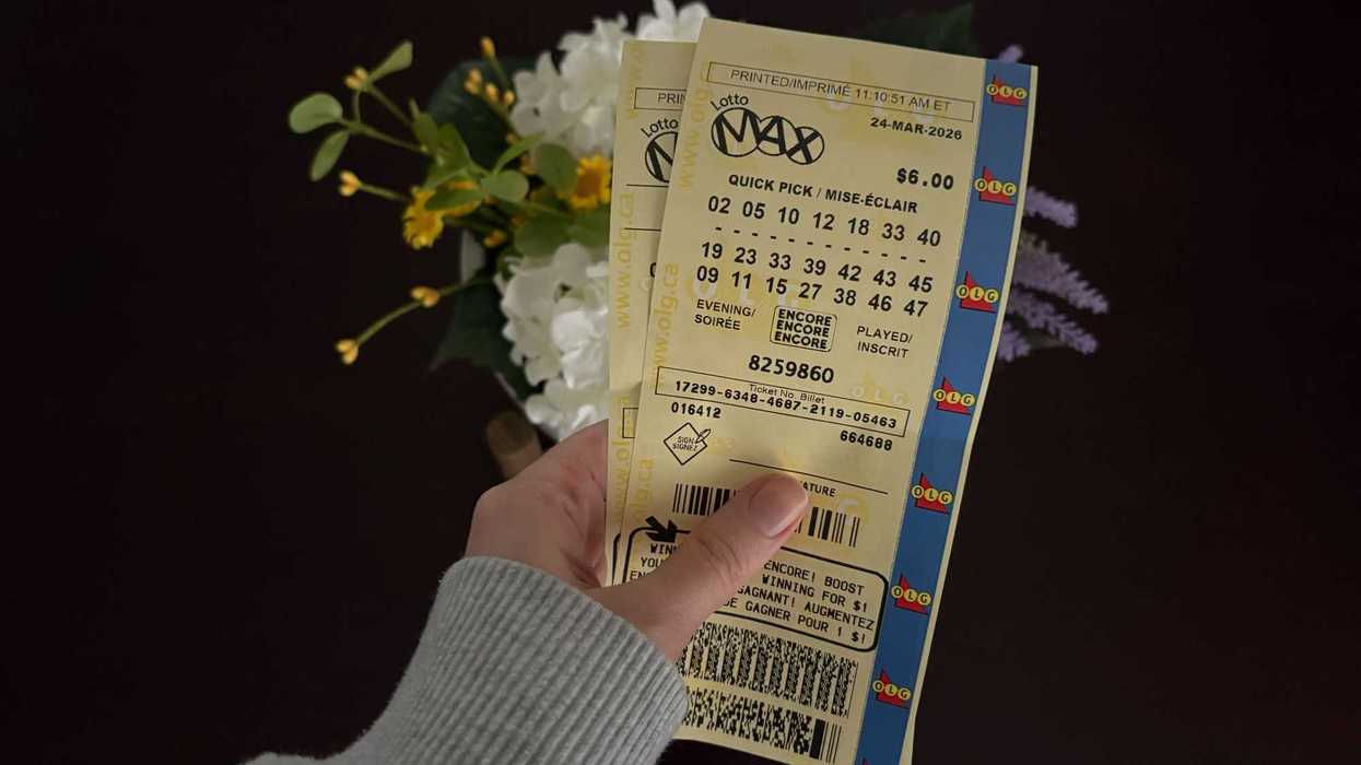 person holding olg lotto max tickets in front of flowers
