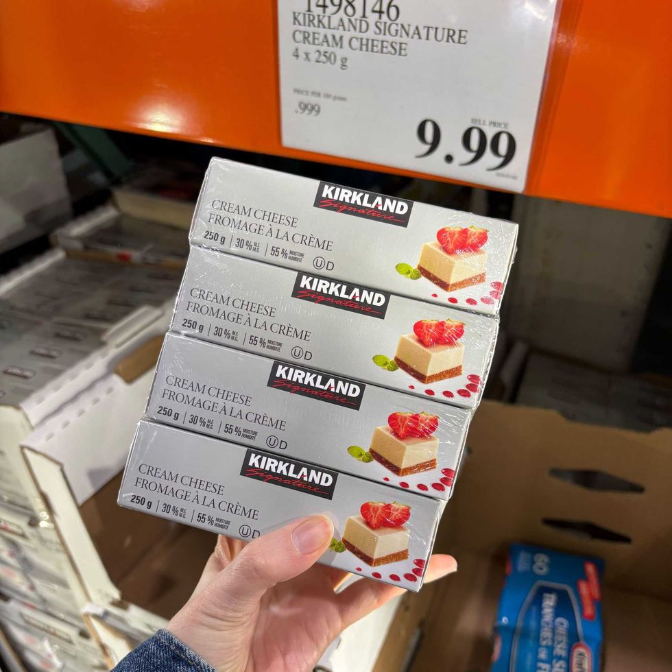 person holding pack of Kirkland Signature cream cheese at costco
