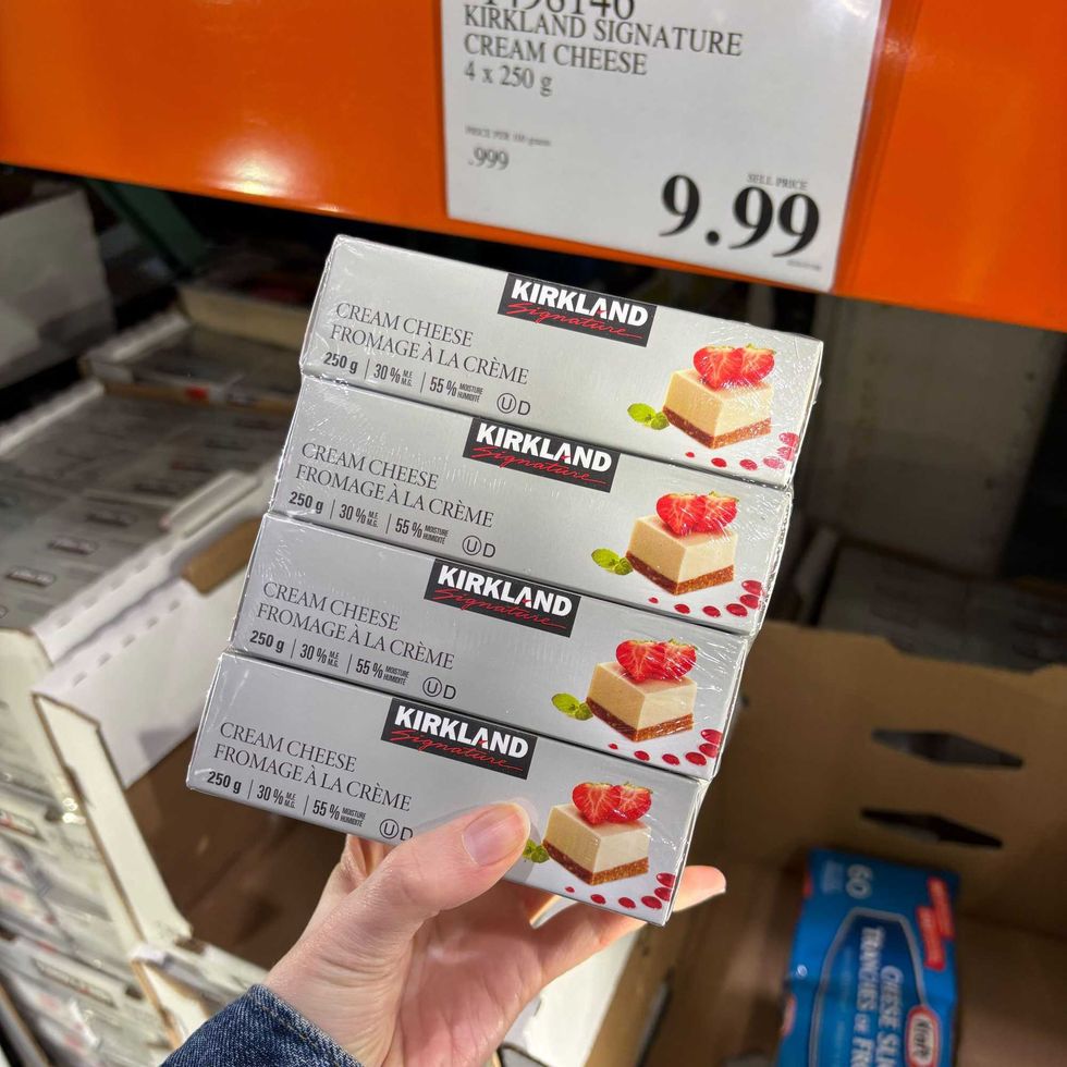 person holding pack of Kirkland Signature cream cheese at costco