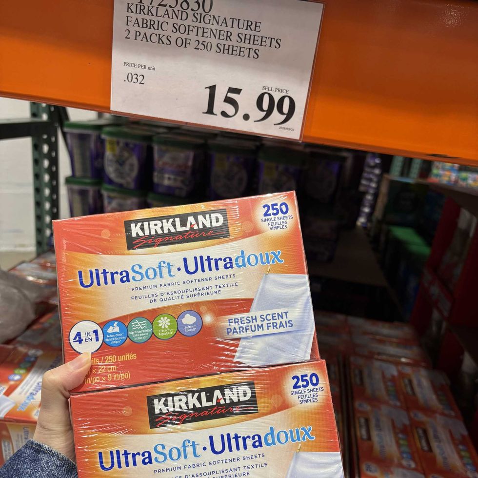 person holding pack of Kirkland Signature dryer sheets at costco
