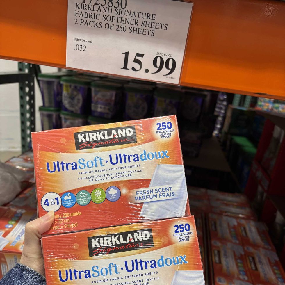 person holding pack of Kirkland Signature dryer sheets at costco