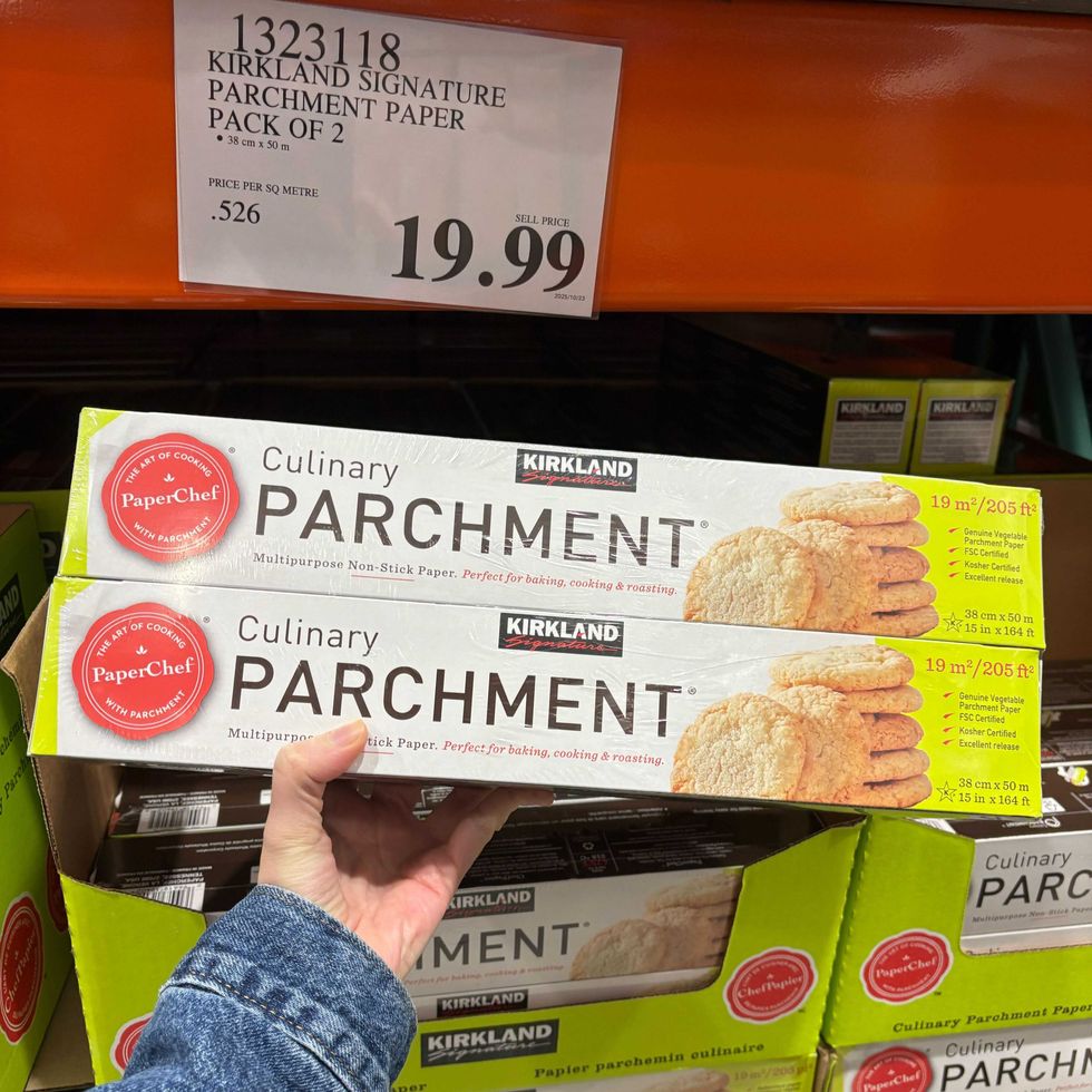 person holding pack of kirkland signature paperchef parchment paper at costco