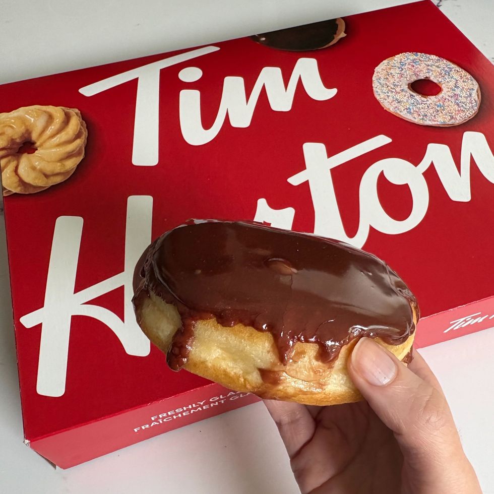 person holding tim hortons boston cream donut