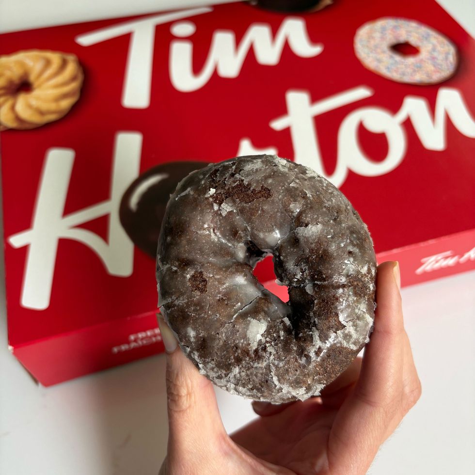 person holding tim hortons chocolate glazed donut