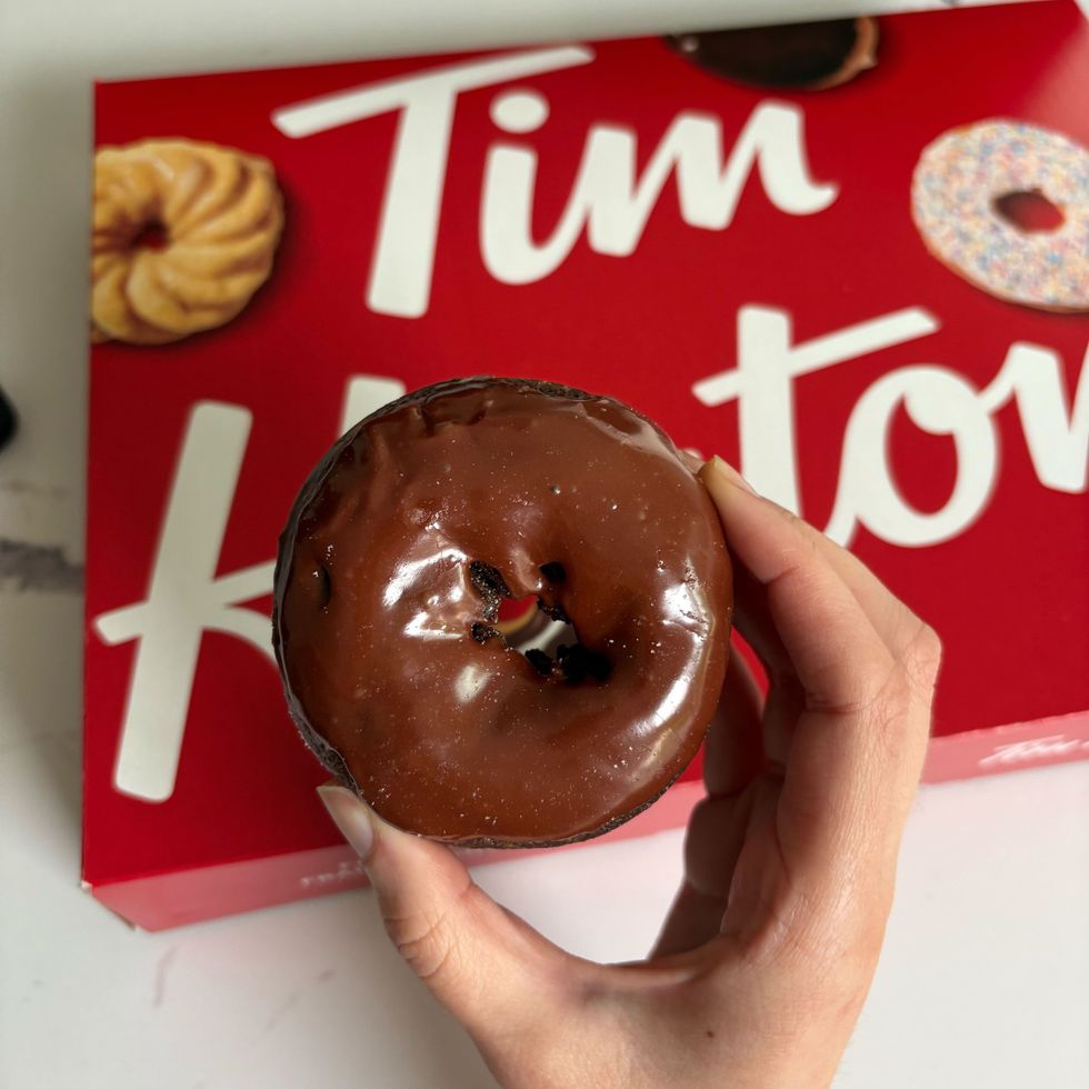 person holding tim hortons double chocolate donut
