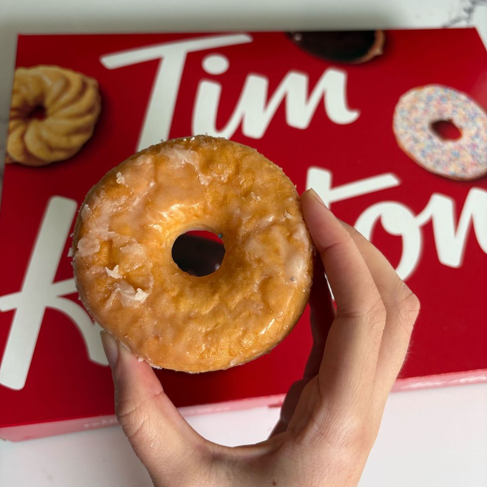 person holding tim hortons honey dip donut