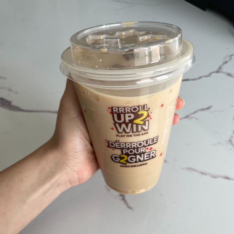 person holding tim hortons iced coffee