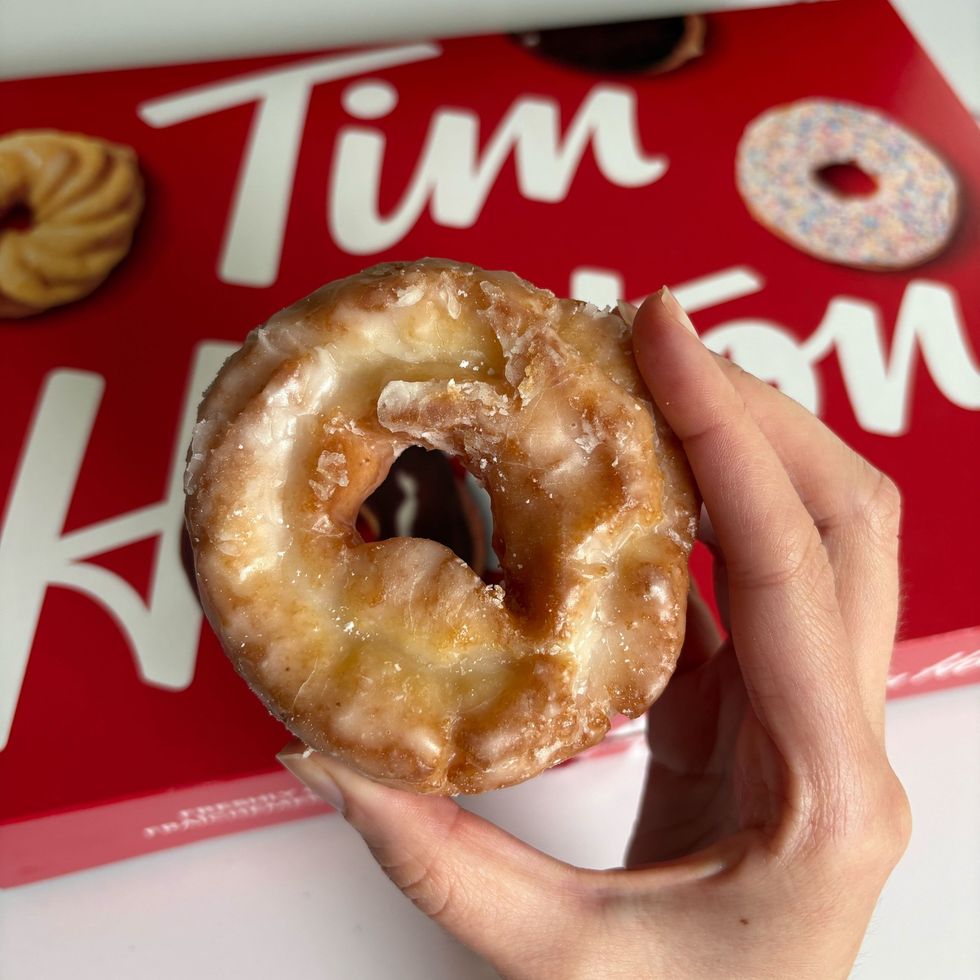 person holding tim hortons sour cream glazed donut