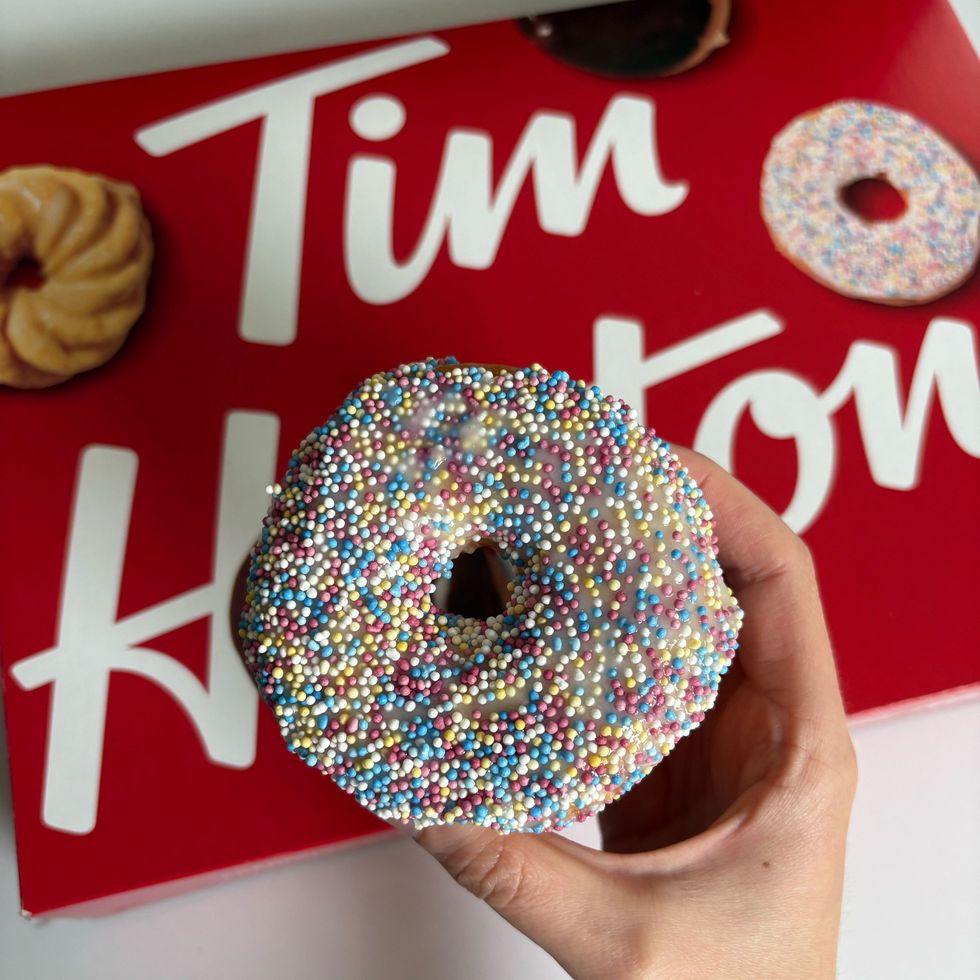 person holding tim hortons vanilla dip donut