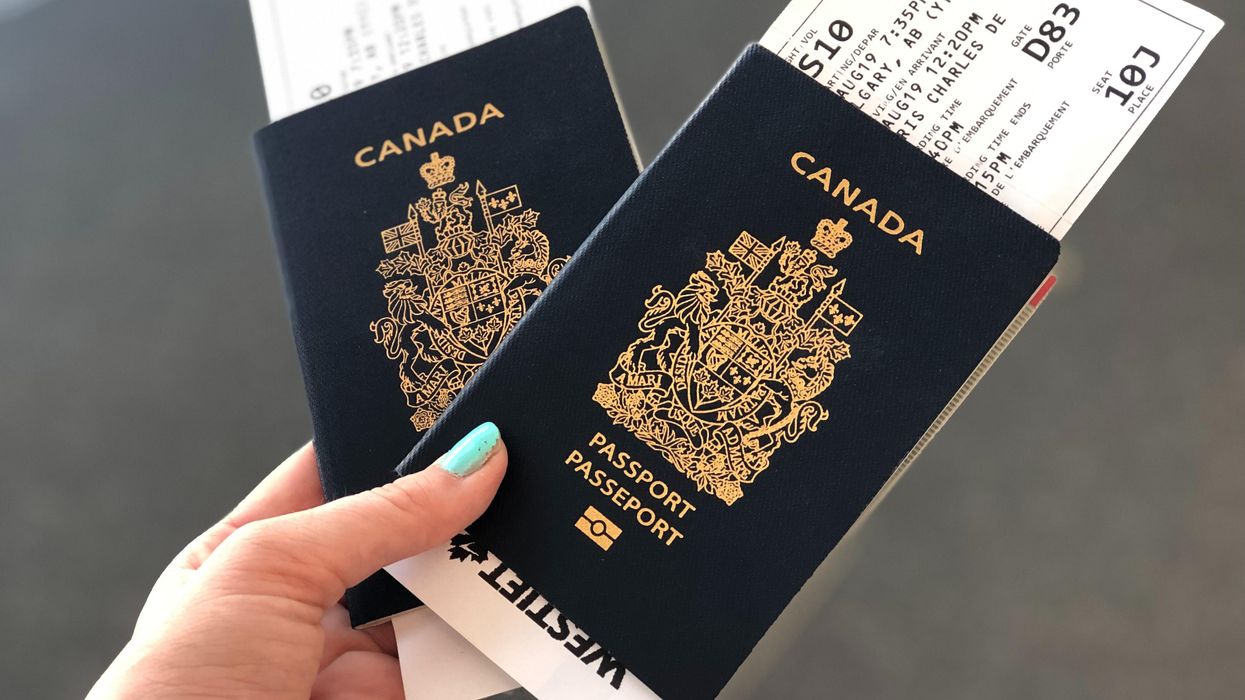 Person holding two Canadian passports with boarding passes.