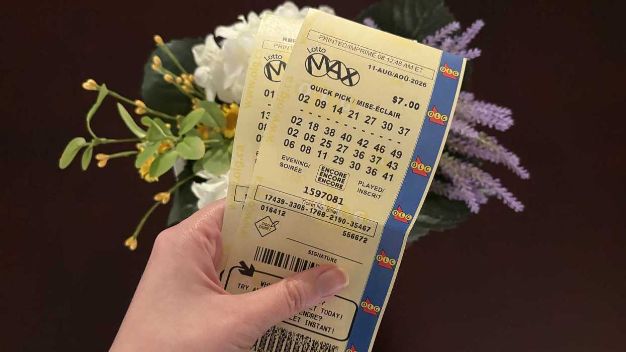 person holding two lotto max tickets above flowers