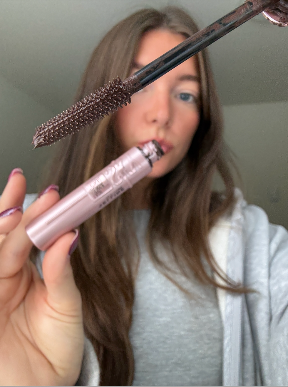 Person holding up a mascara tube.