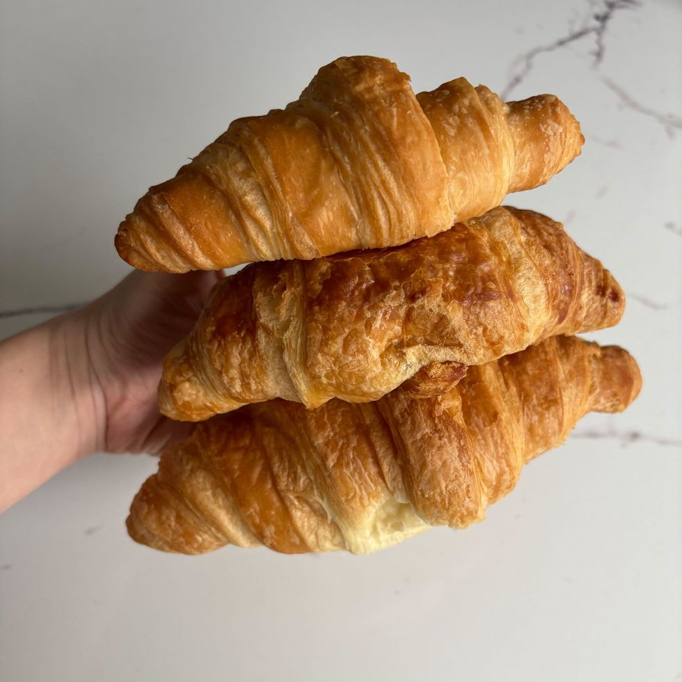 person holding walmart, loblaws and costco croissants