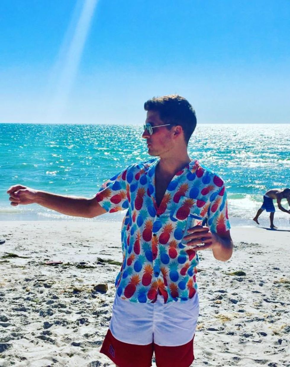 person on a beach holding a drink wearing the pineapple shirt